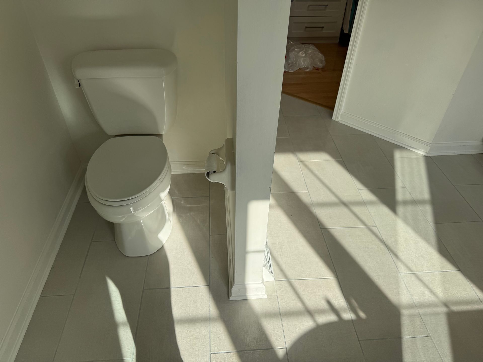 A toilet is sitting in a bathroom next to a window.