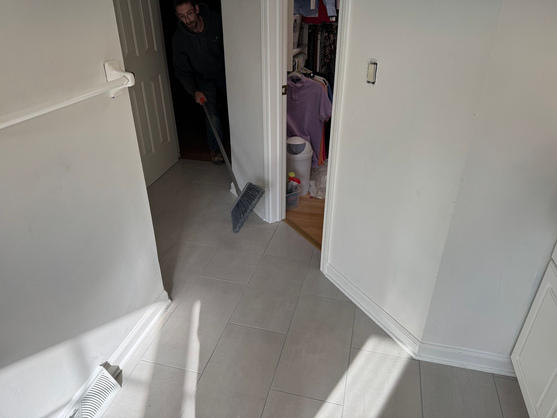 A man is mopping the floor in a closet.