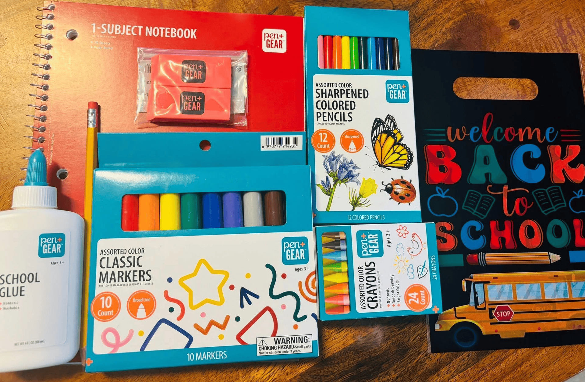 Back-to-school supplies including glue, notebooks, colored pencils, markers, crayons, and a 