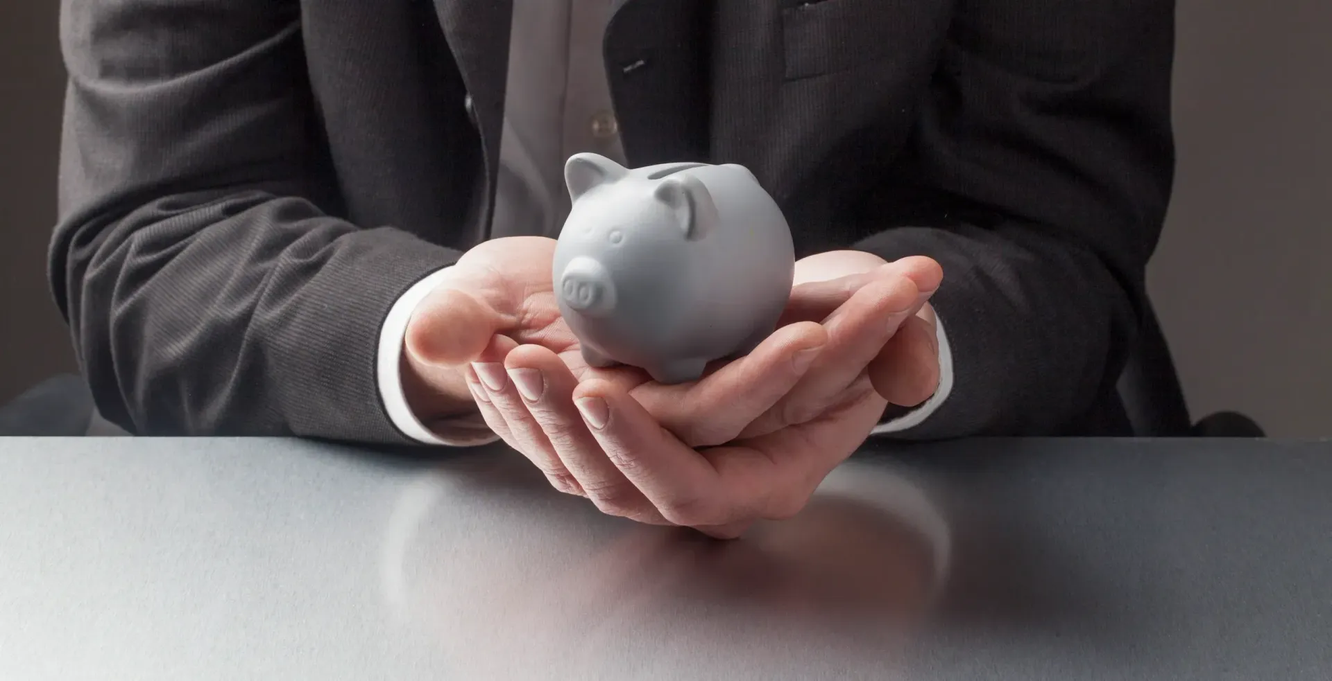 A man in a suit is holding a piggy bank in his hands.