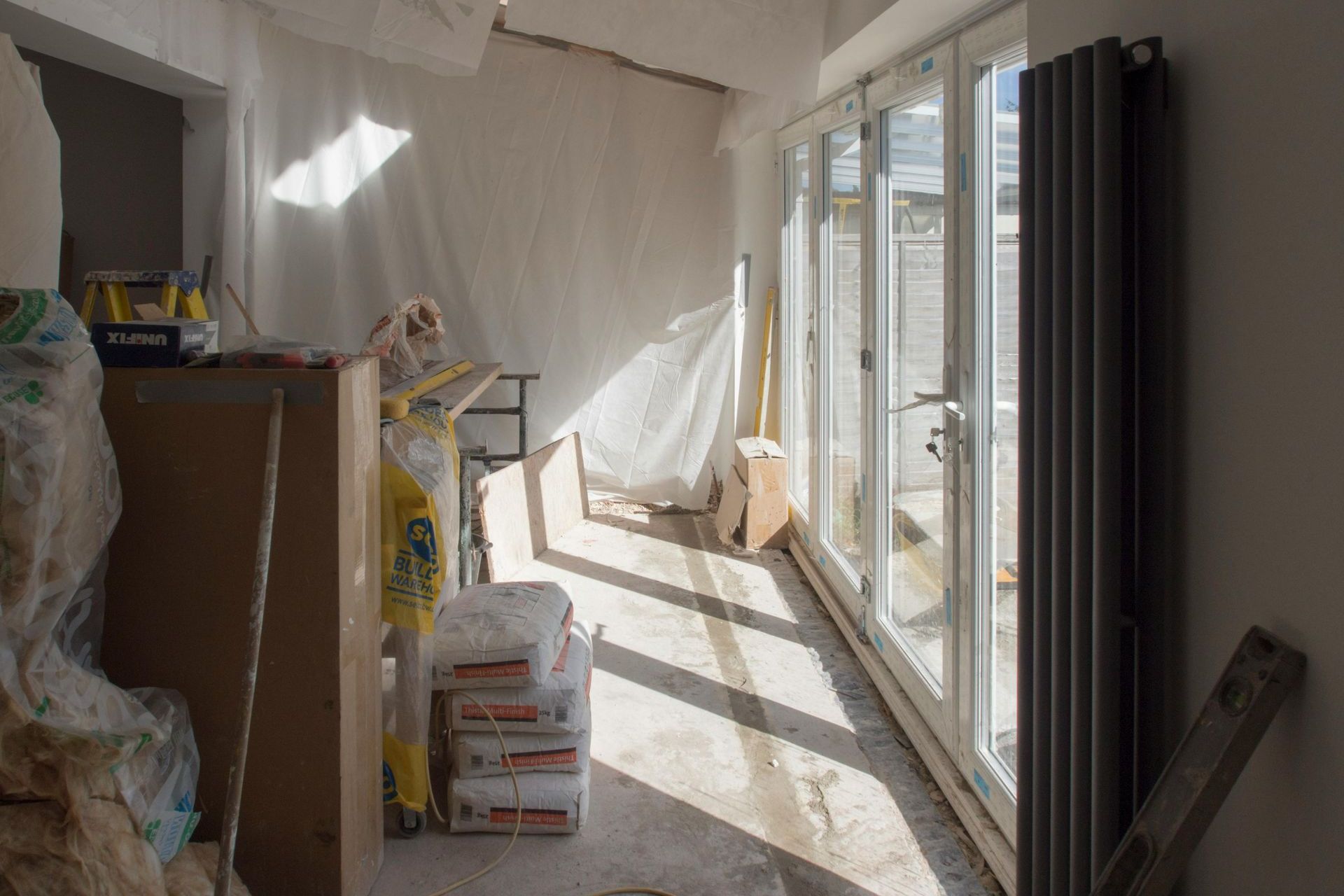A room is being remodeled with a lot of bags of cement on the floor.
