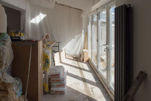 A room is being remodeled with a lot of bags of cement on the floor.