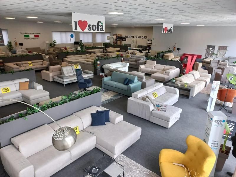 Uno showroom che espone numerosi divani di vari colori e stili, con un cartello con la scritta 