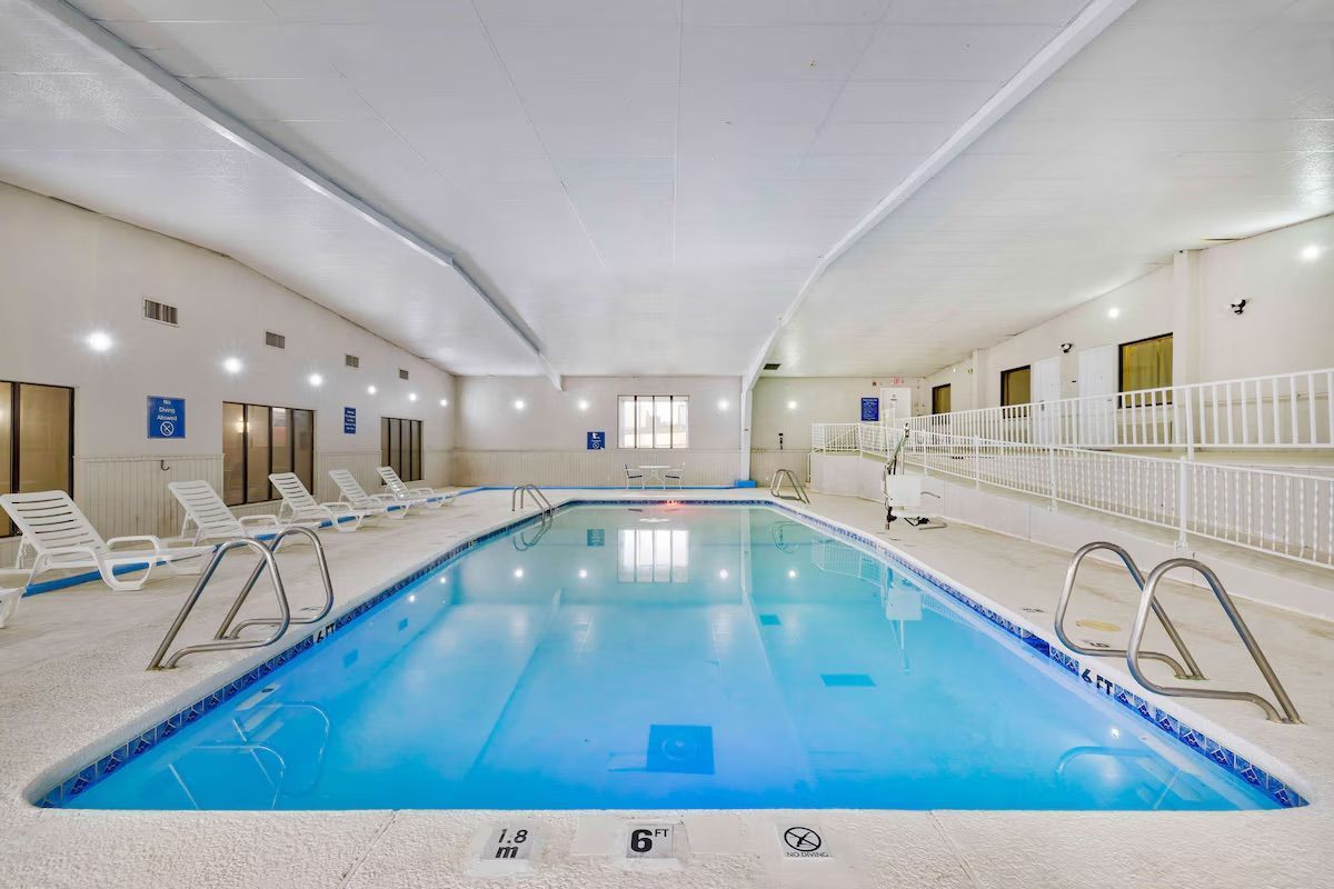 Una gran piscina cubierta en un hotel con sillas alrededor.