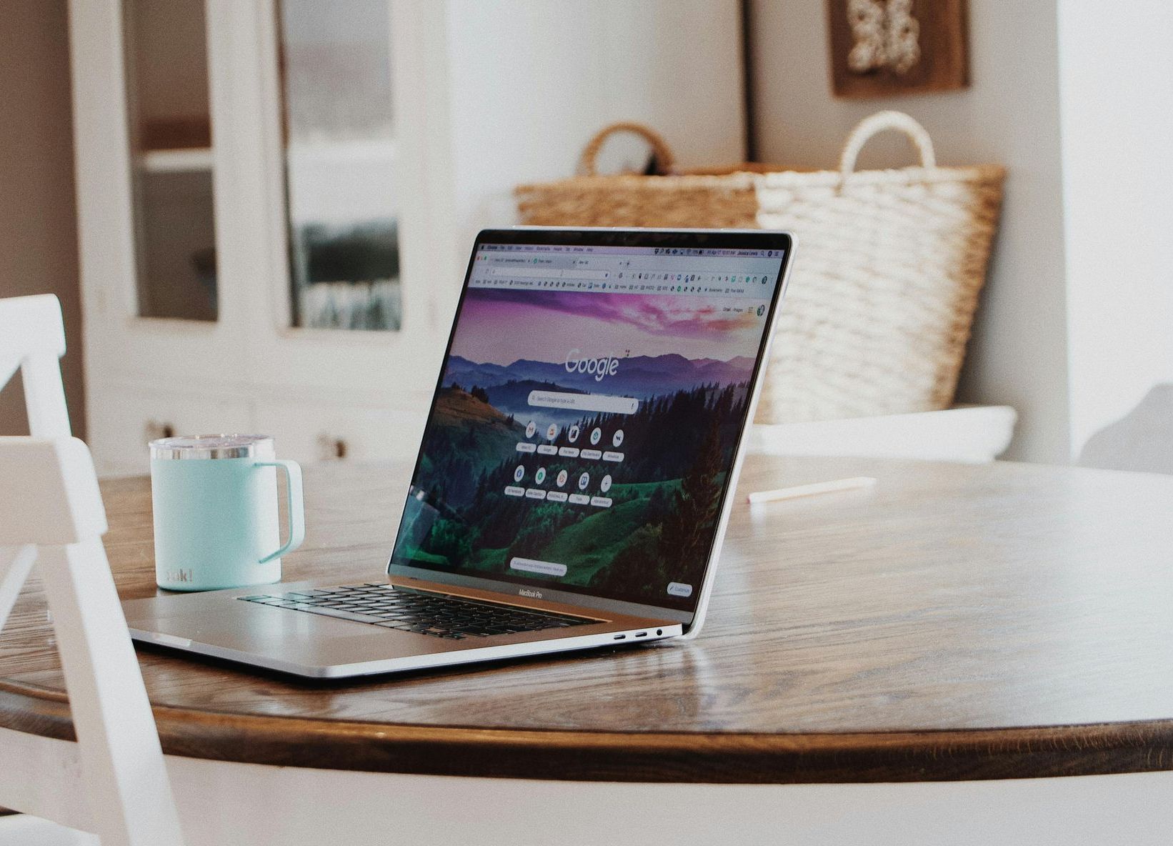 A laptop is sitting on a wooden table next to a cup of coffee.