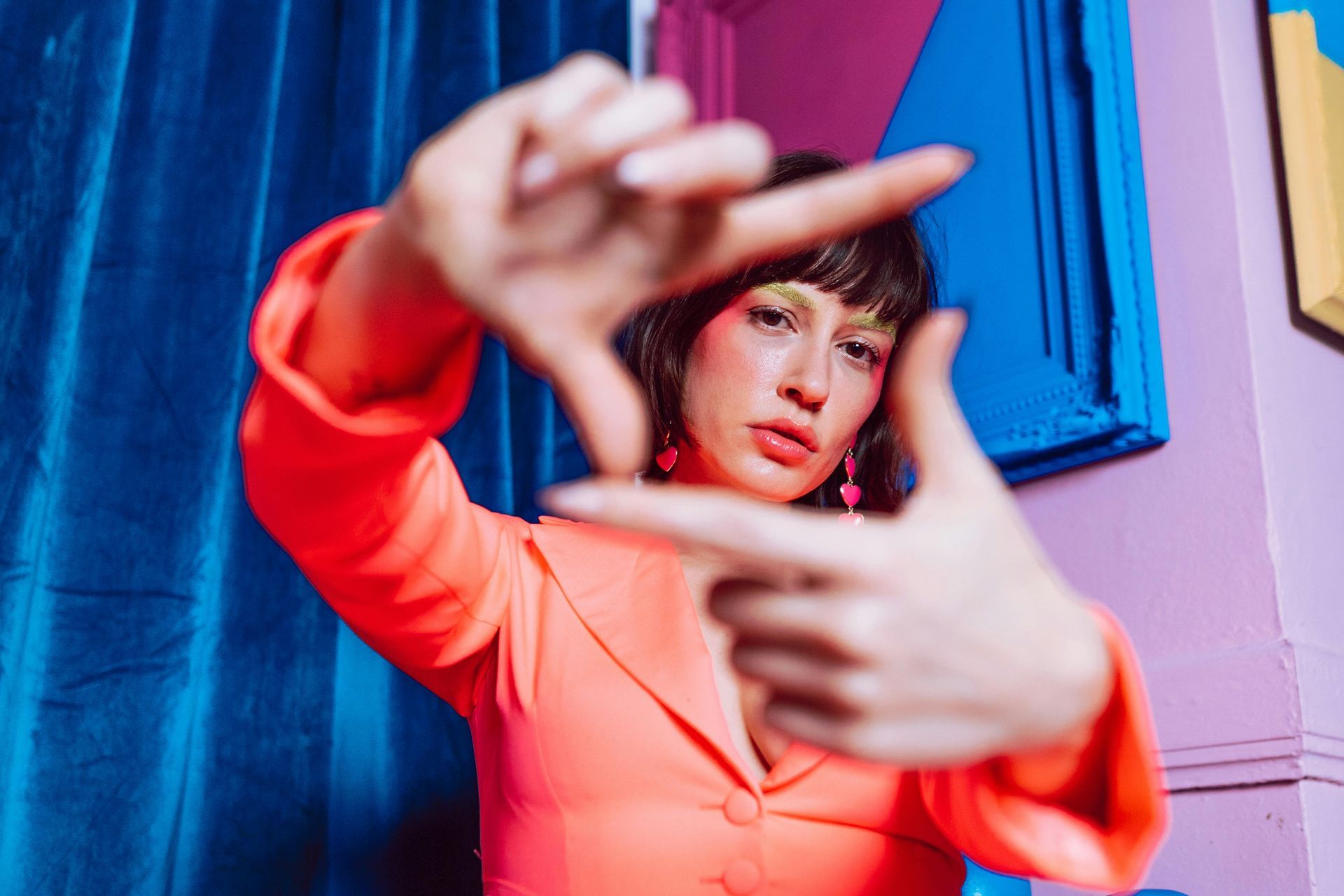A woman in a pink jacket is making a frame with her hands.