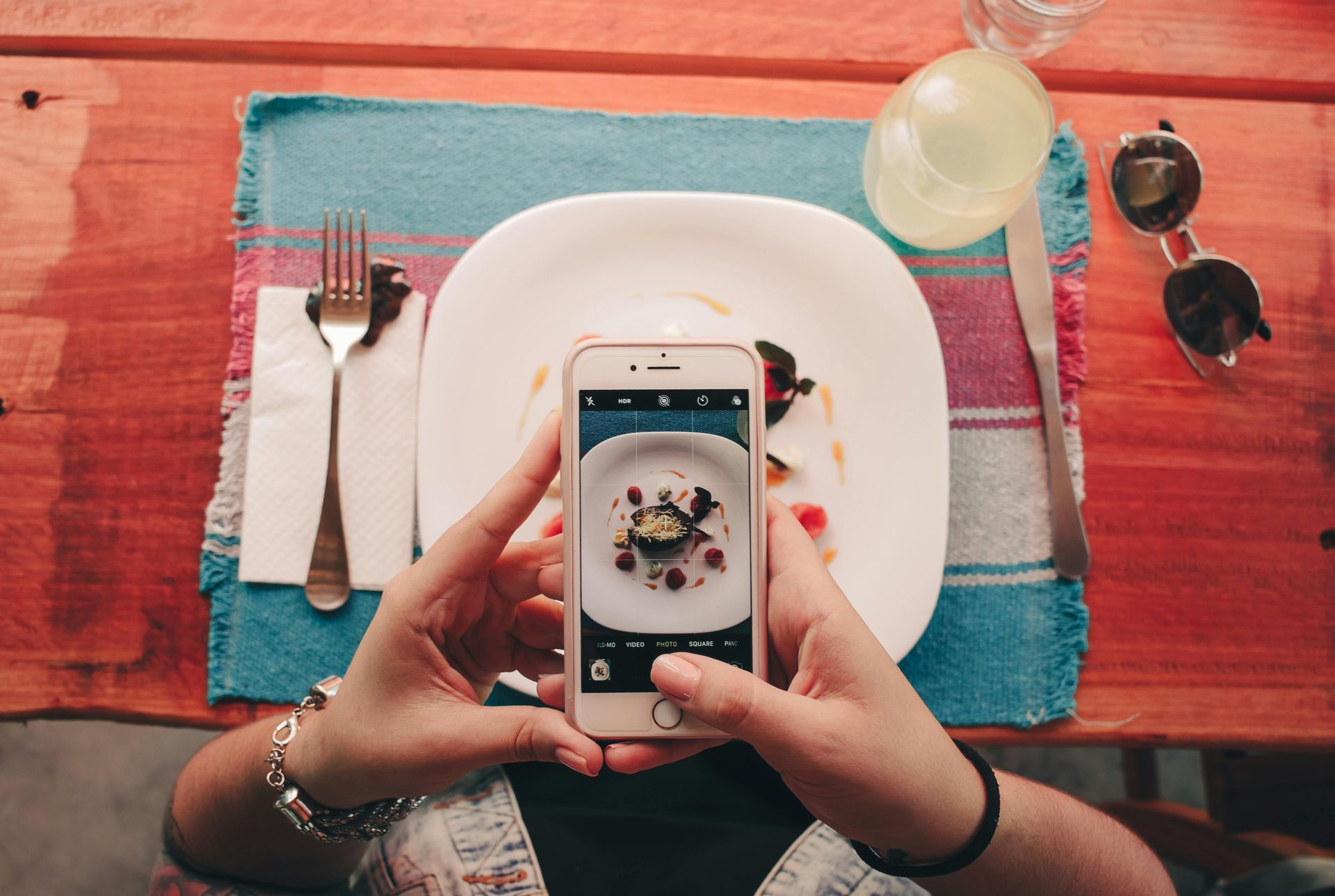 A person is taking a picture of a plate of food with a cell phone.