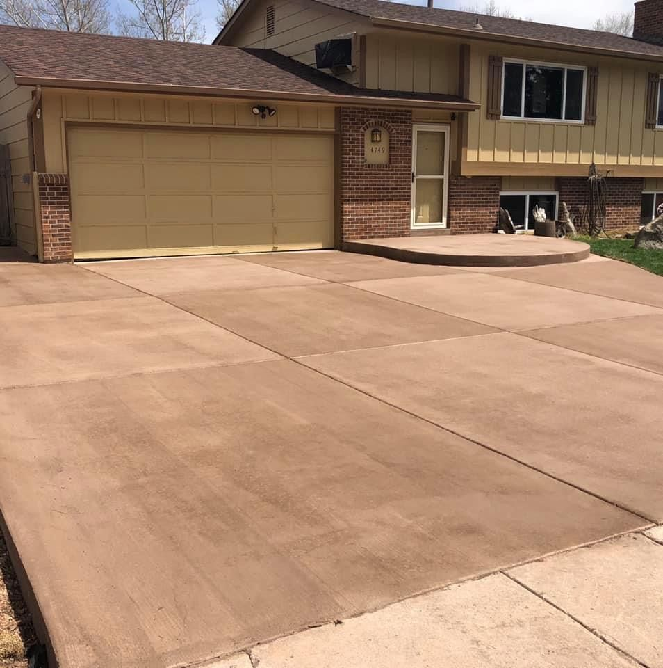 Suburban house with a two-car garage and wide concrete driveway under bright daylight