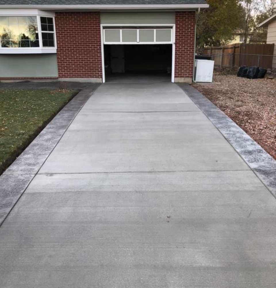 Concrete driveway leading to a brick house garage with an open door
