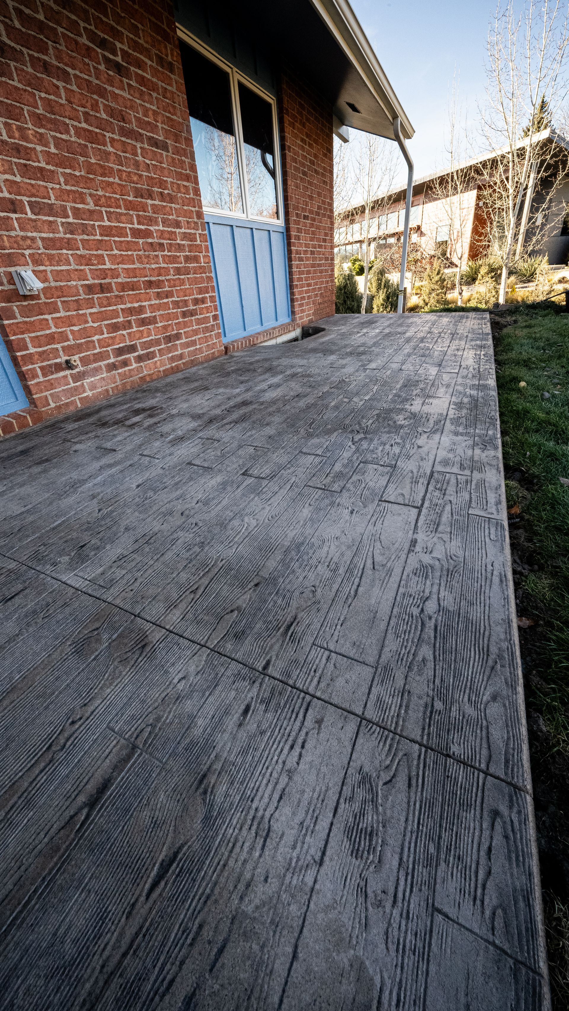 Brick house side patio with weathered gray concrete and blue double doors