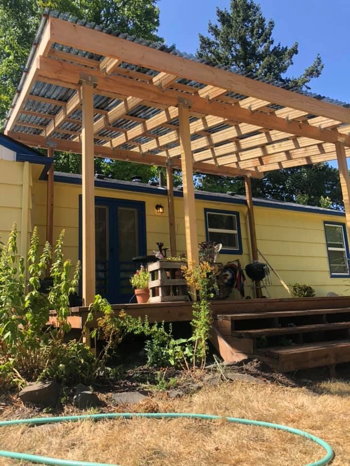 Yellow house with a wooden deck and pergola in a yard.