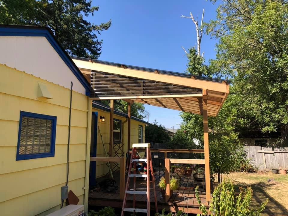 Yellow house with a wooden pergola over a deck. A ladder leans against the deck.