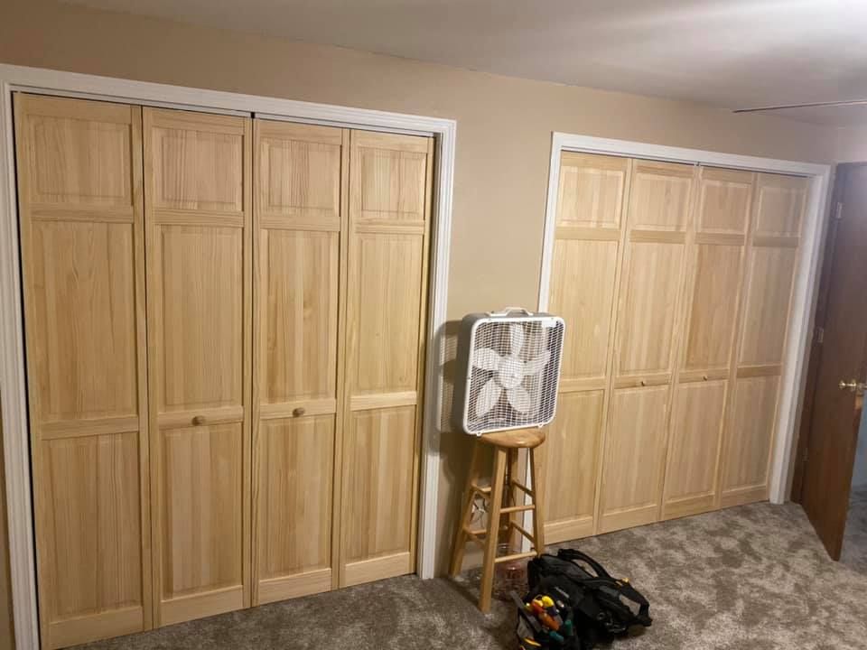 Two wooden bi-fold closet doors with a fan and tools in between.