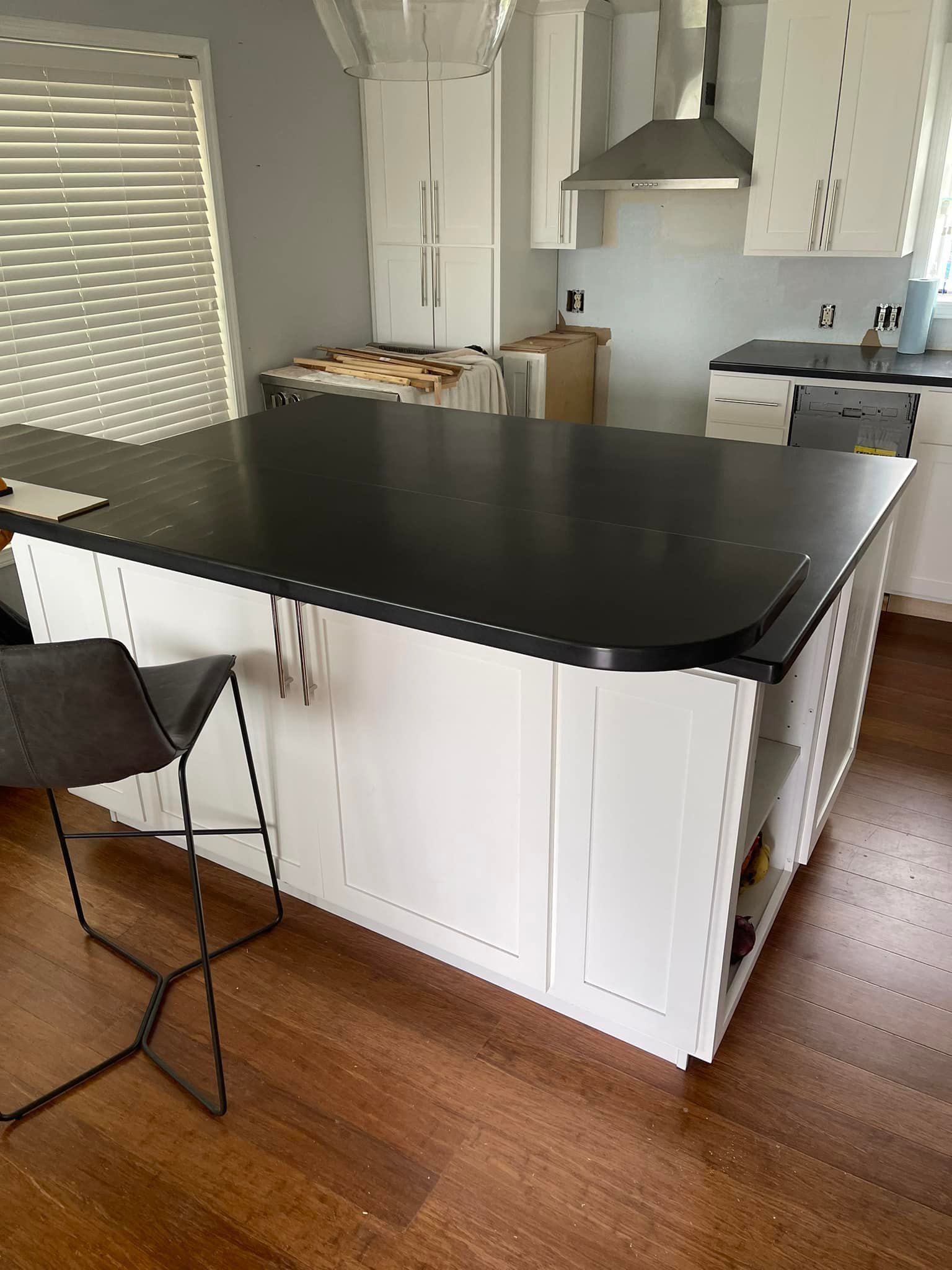 White kitchen island with a black countertop and a gray barstool.