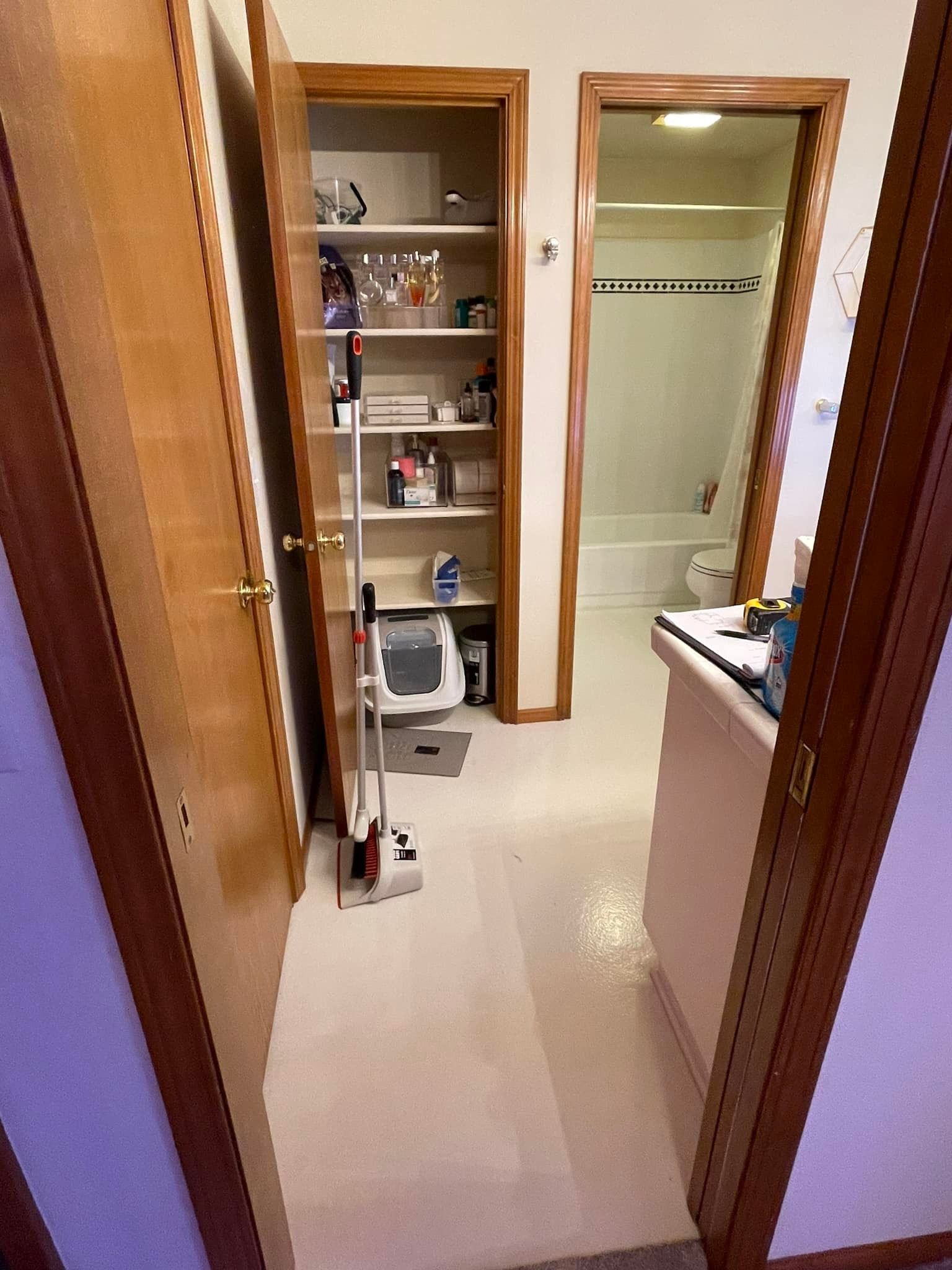 Hallway with closet, bathroom entrance, and storage. Vacuum cleaner and storage items are visible.