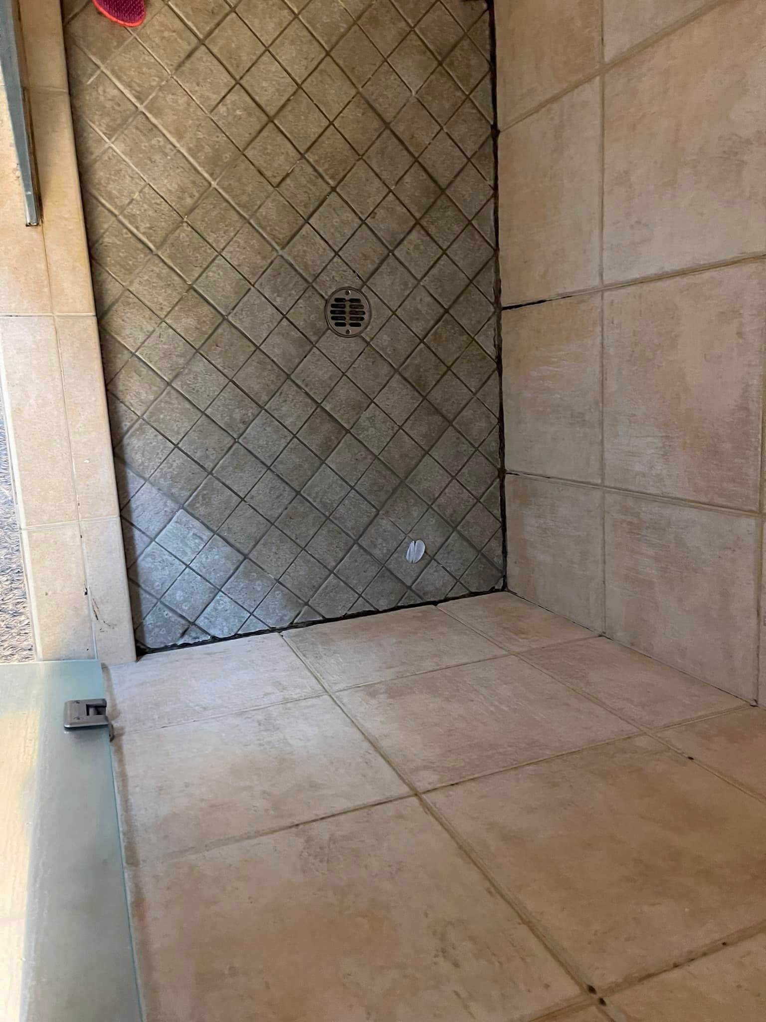 Shower with stone tile walls and floor, diagonal pattern on back wall.