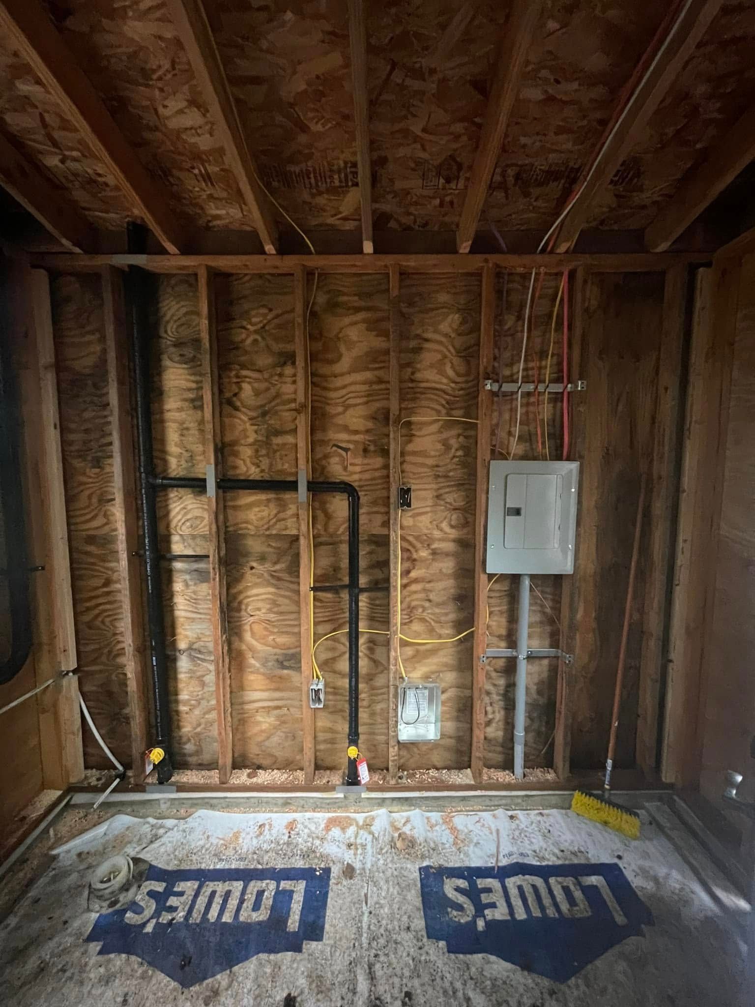 Interior of unfinished construction; wood framing, exposed plumbing and electrical components.