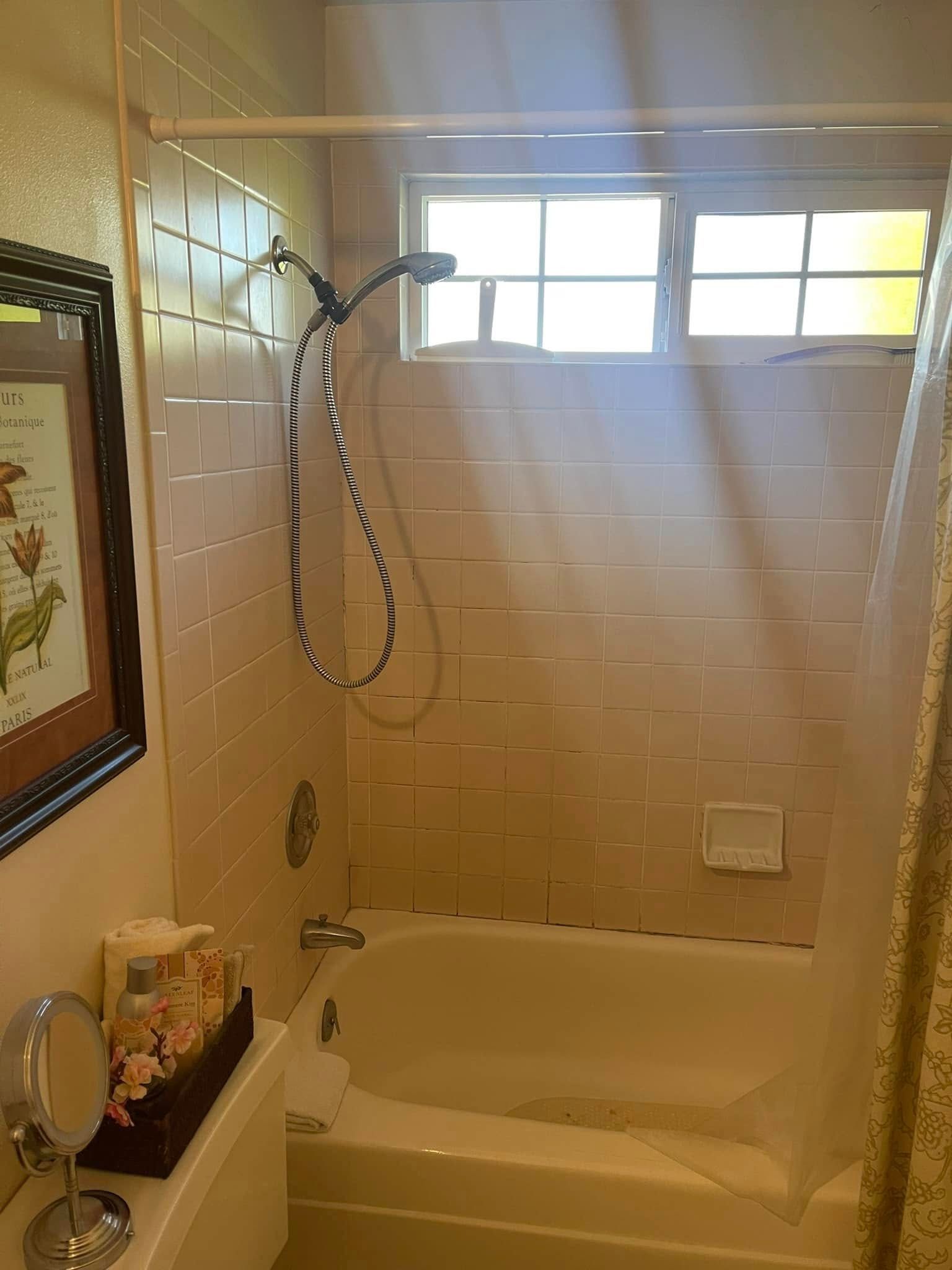 Bathroom with pink tile, a white bathtub, and a shower curtain.