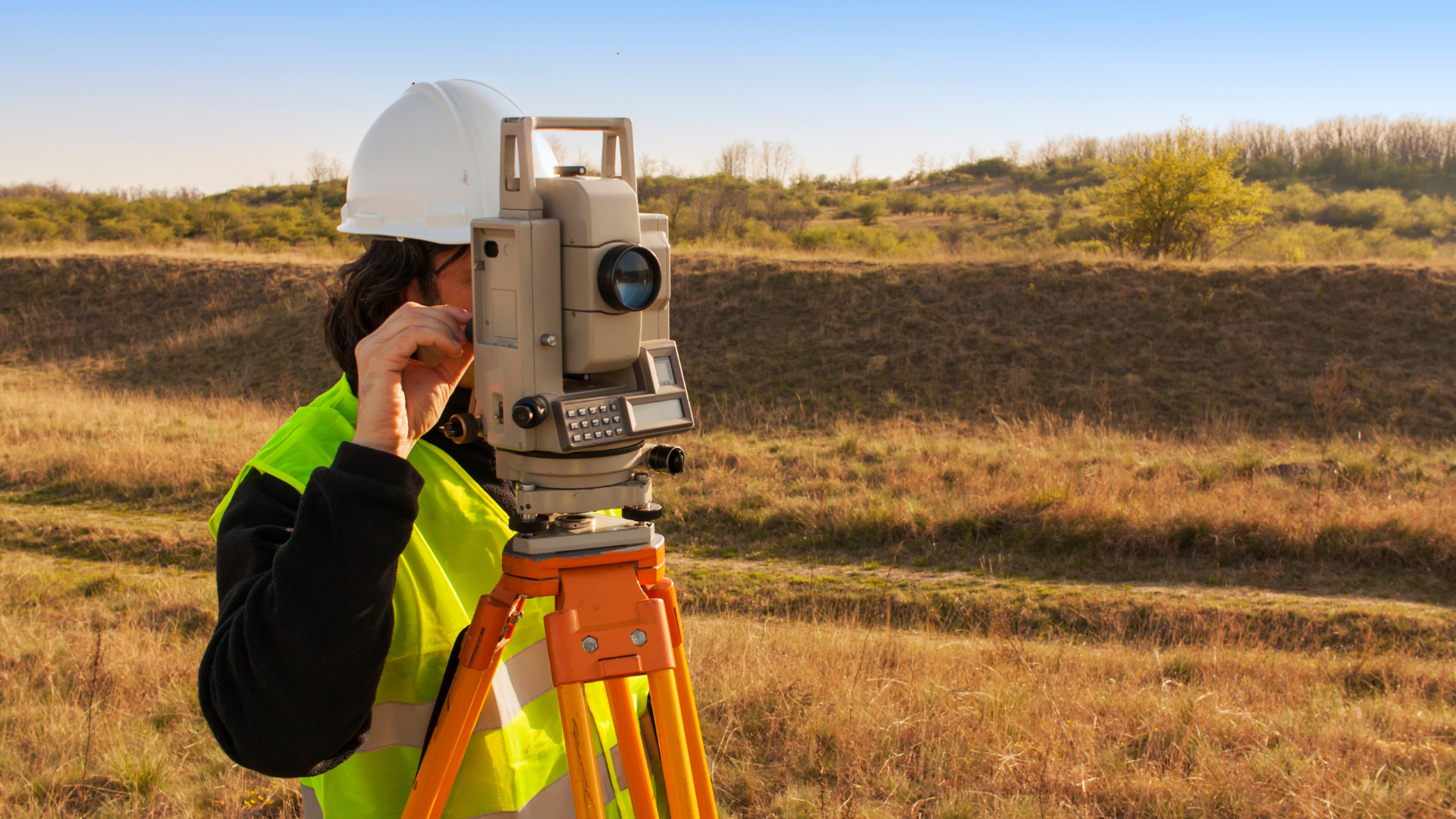 A man is using a theodolite in a field.