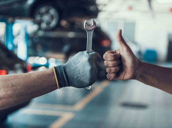 close up thumb-up and auto mechanic hand with tool