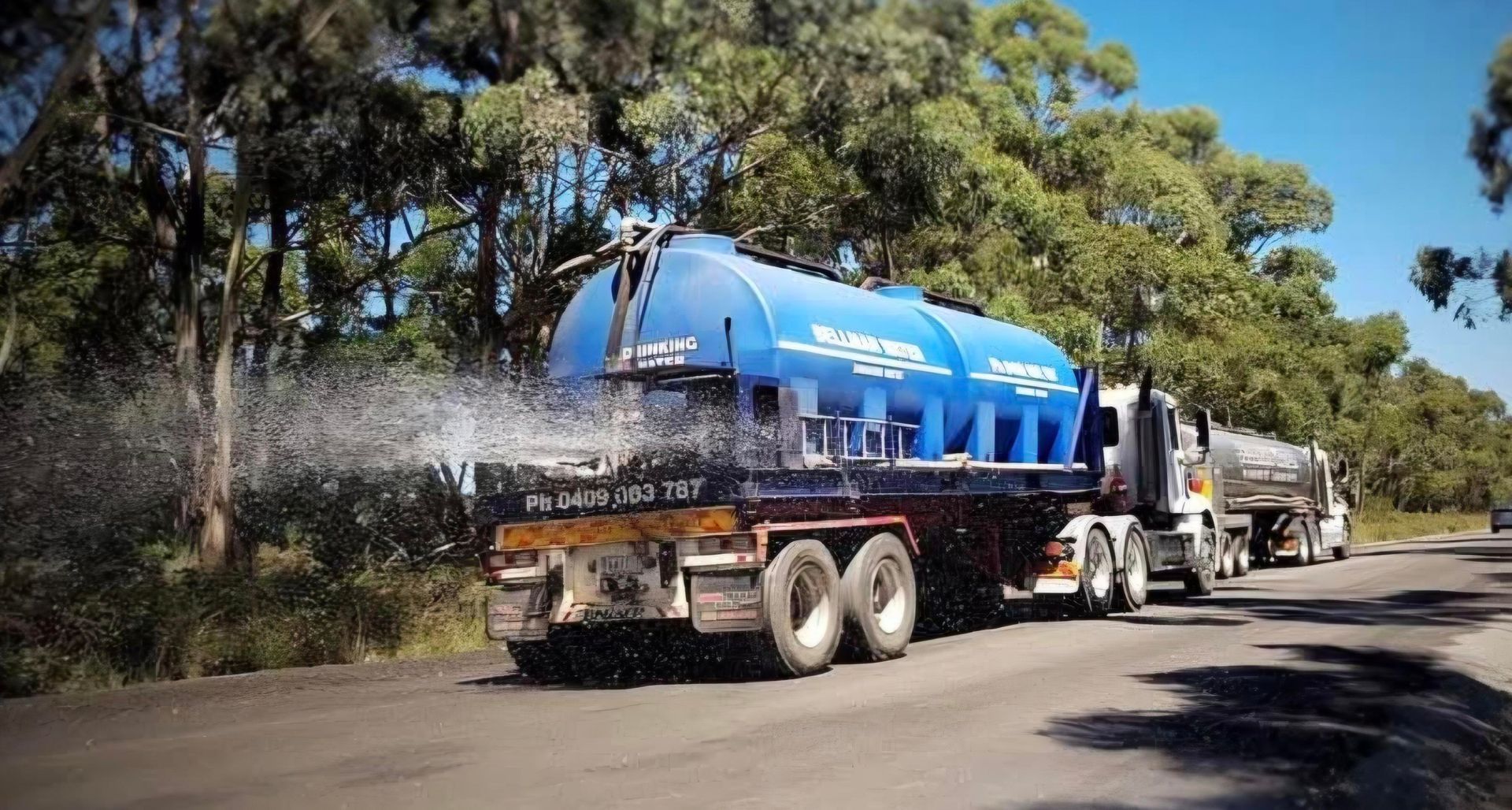 White tanker truck on a wet road at sunset, with sun glare and cloudy sky