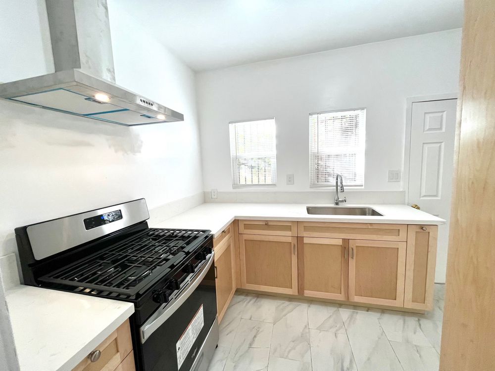 A wooden fence along a sidewalk next to a stone wall.