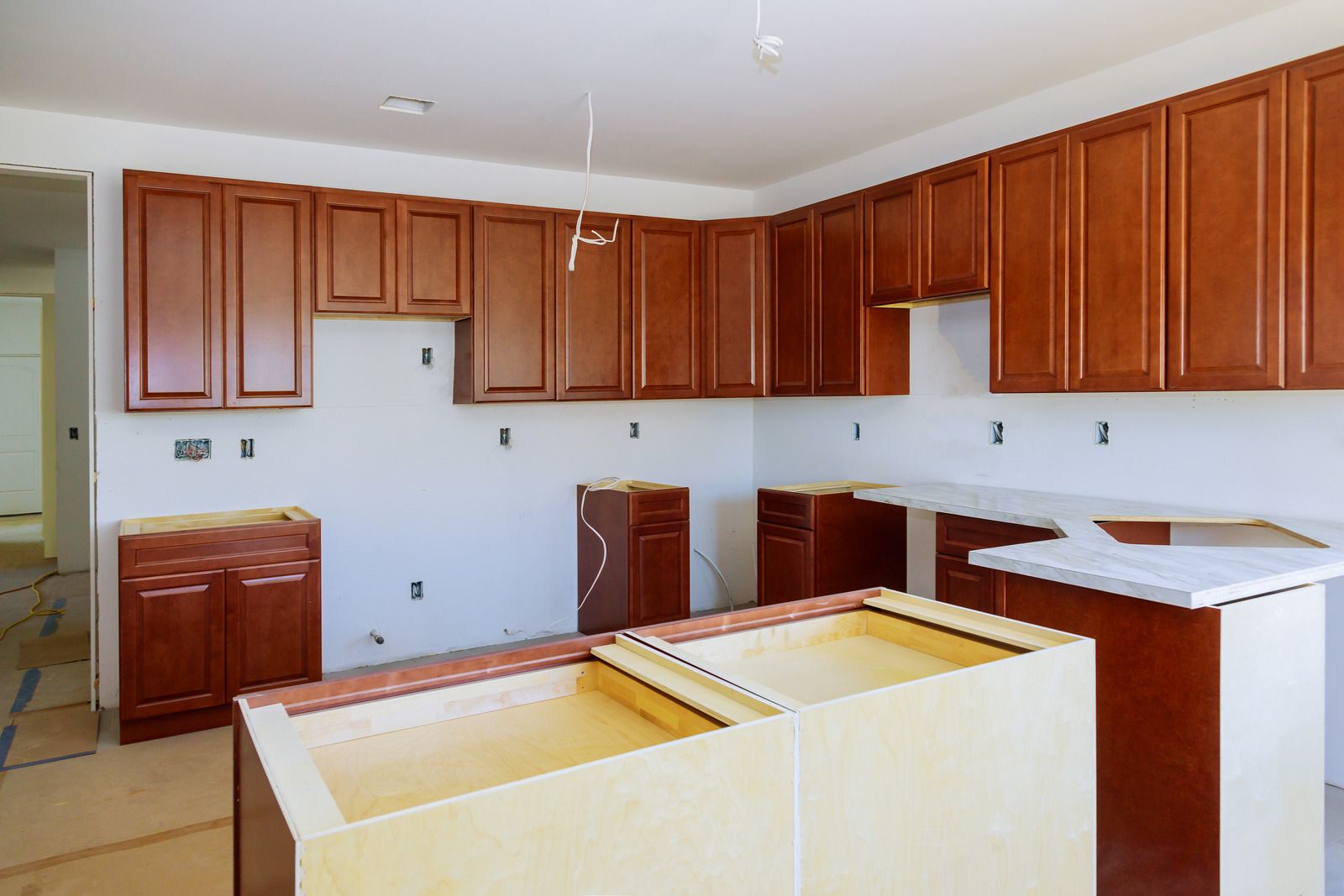 A kitchen under construction with wooden cabinets and white counter tops