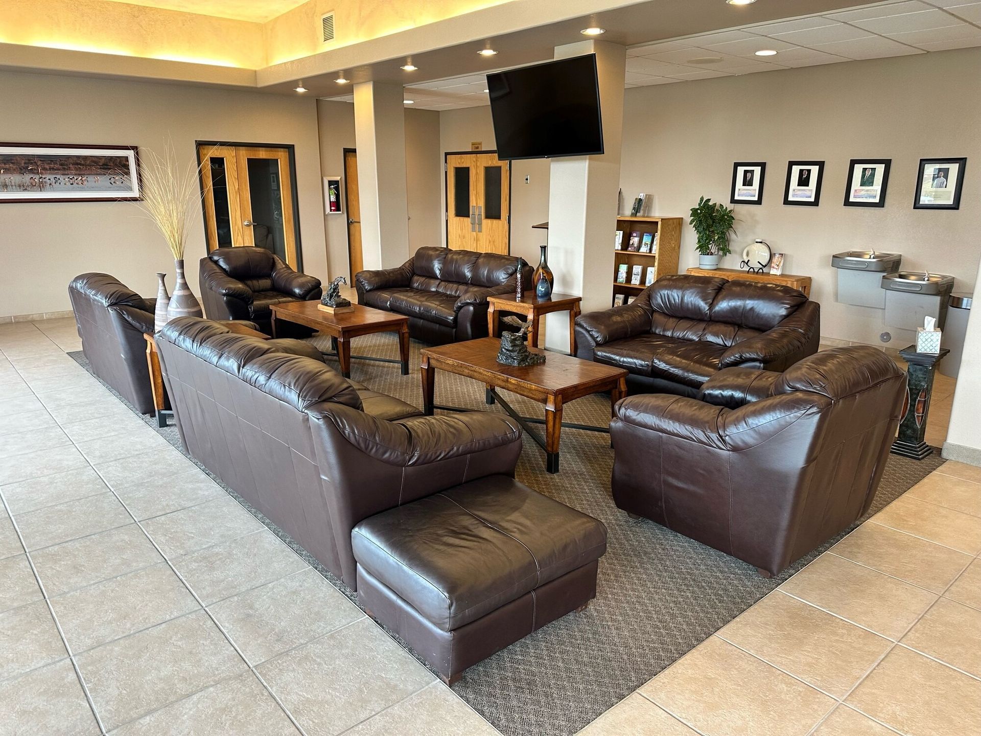 Lounge area with brown leather seating, coffee tables, and a TV mounted on a tan column.