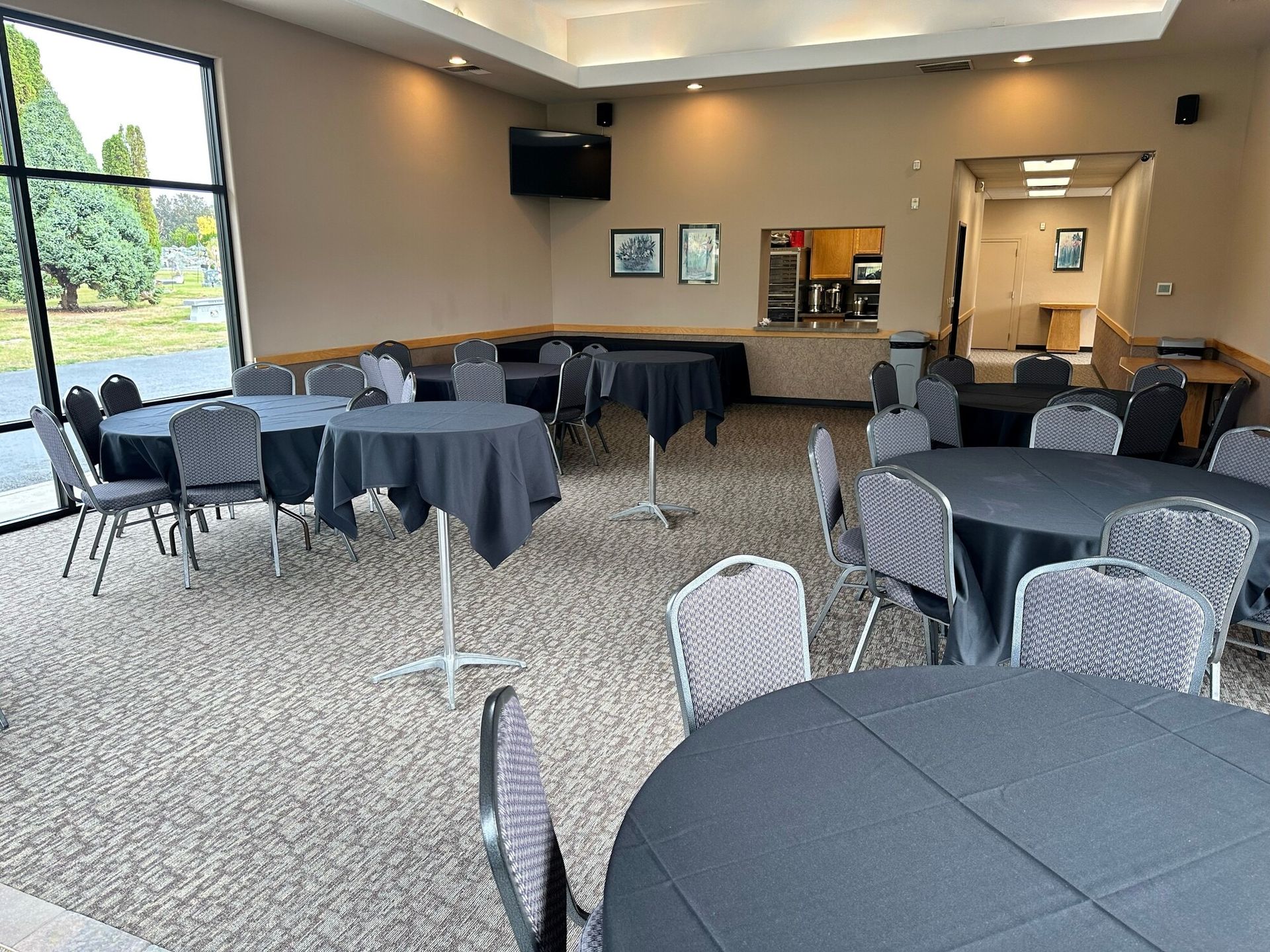 A room with round tables and chairs, some tables covered in black cloth.
