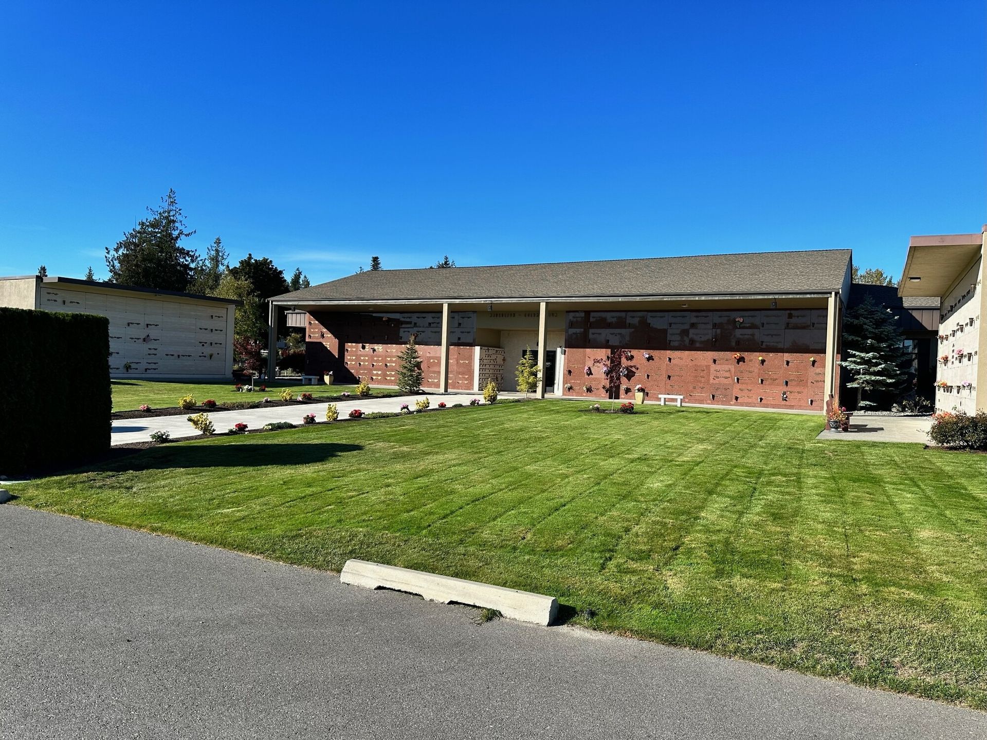 A red brick building with a green lawn under a bright blue sky.