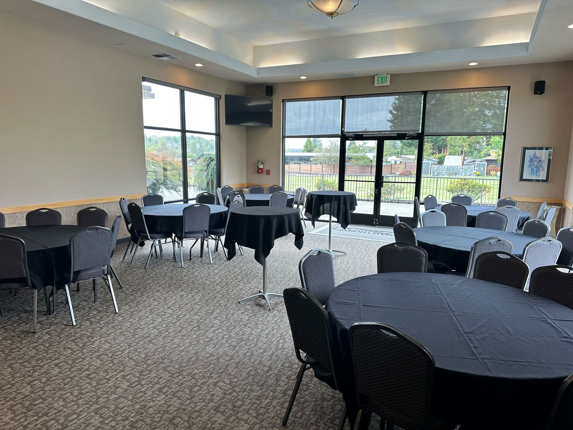 Event room with round tables draped in black, chairs, and large windows.