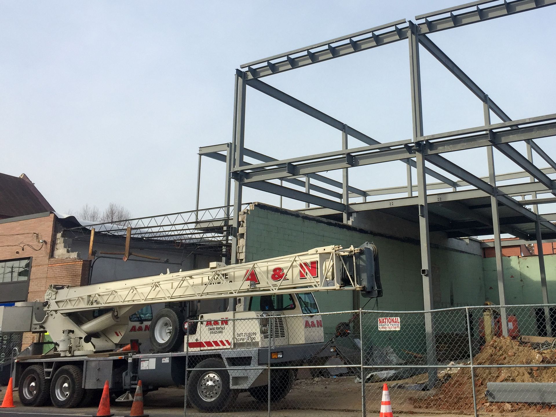 A white crane from A&N Crane Rental is parked in front of a building under construction