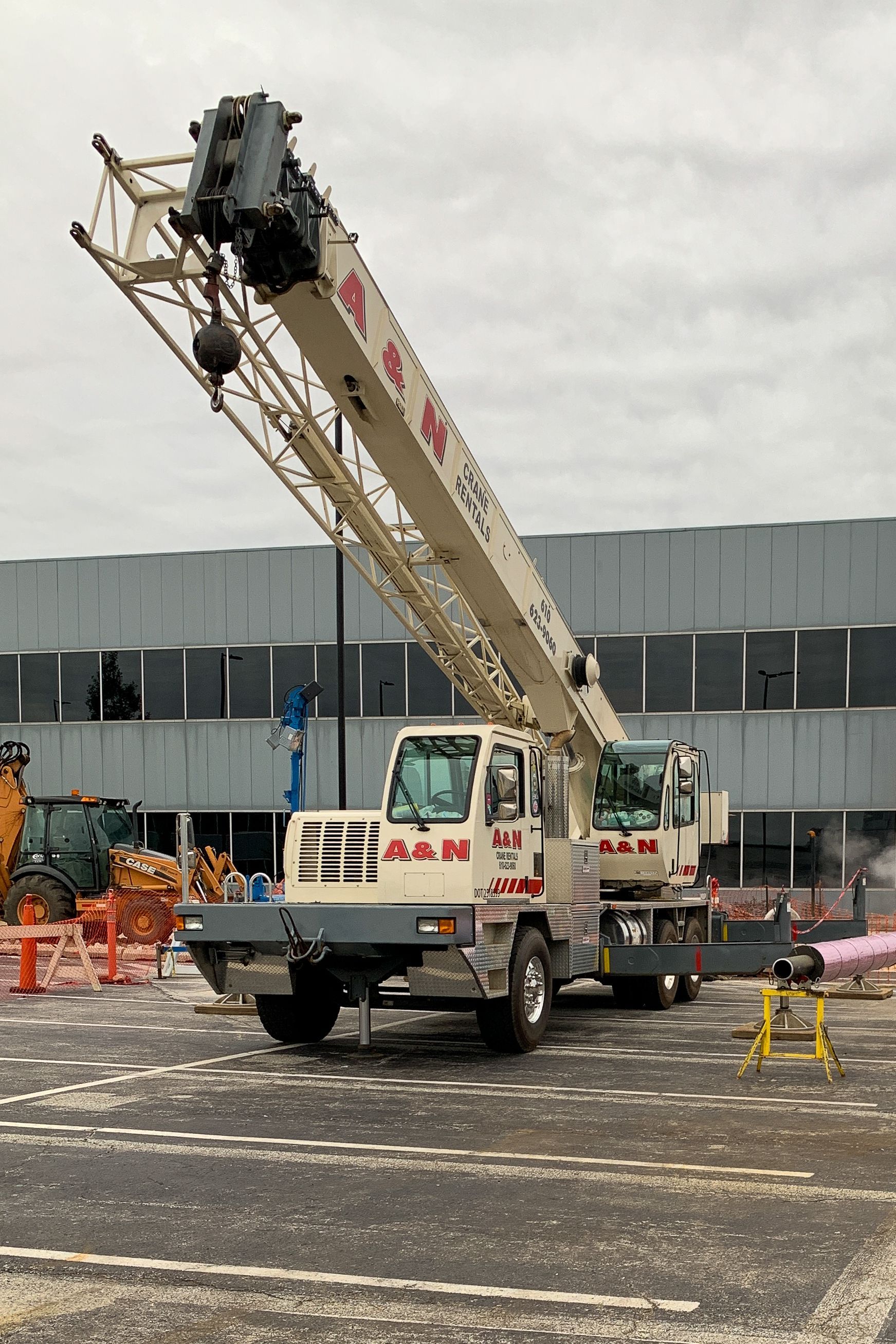A large crane from A&N Crane Rental is parked in a parking lot in front of a building.
