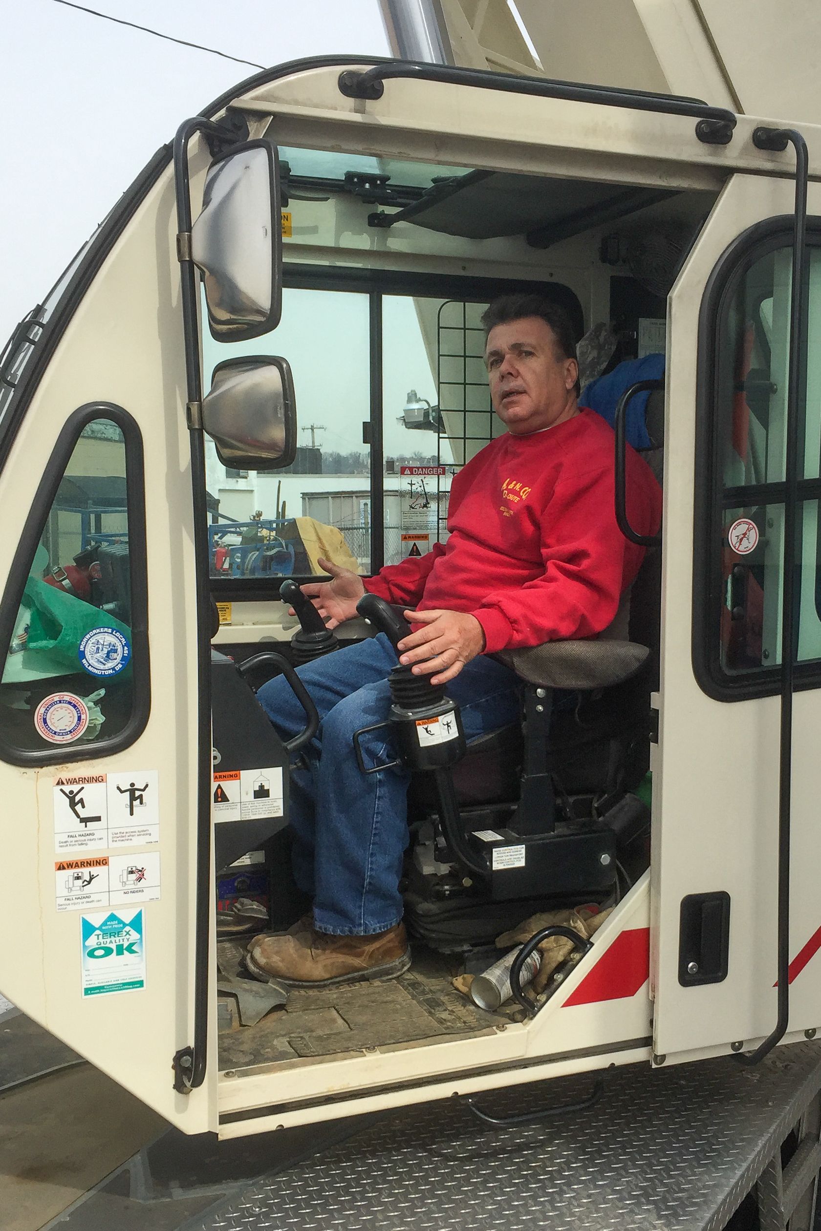 Nick Crocetto Sr. in a red shirt is sitting in the driver 's seat of an A&N Crane Rental crane. .