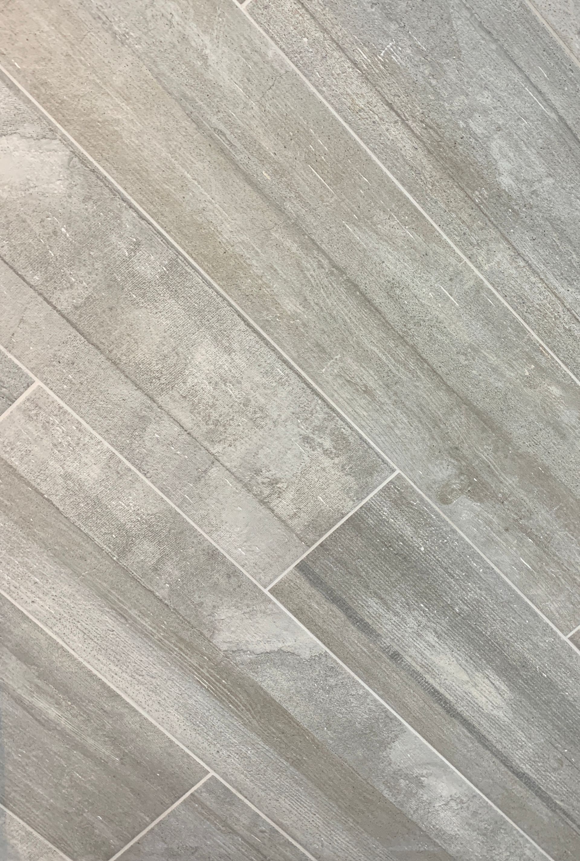 A close up of a gray tile floor that looks like wood.