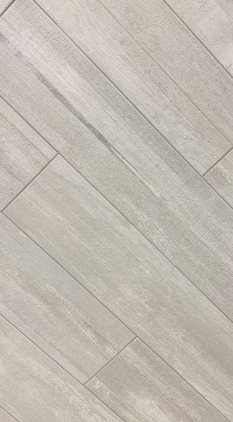 A close up of a white tile floor that looks like wood.