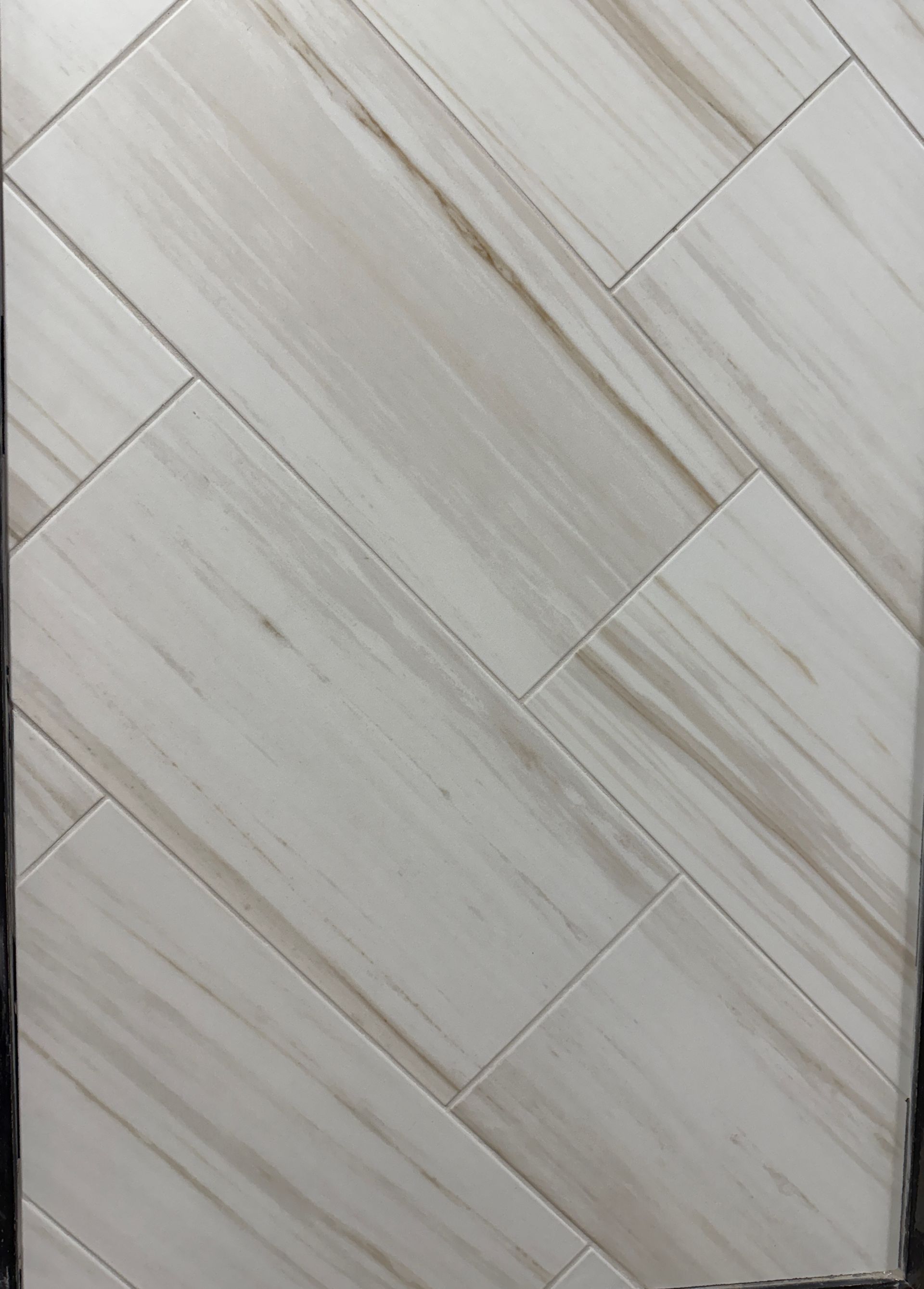 A close up of a white tile floor that looks like wood.