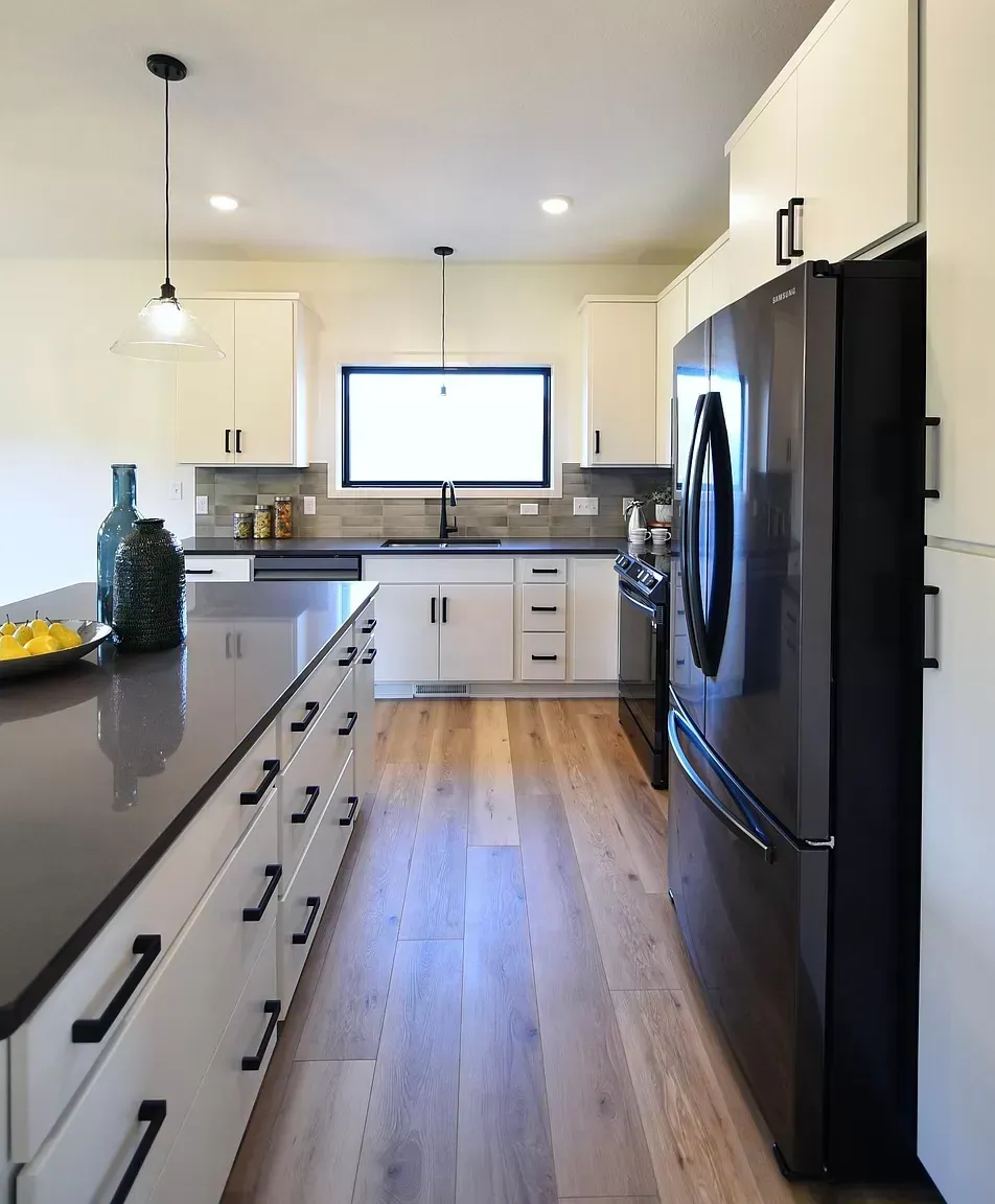 A kitchen with white cabinets and a black refrigerator
