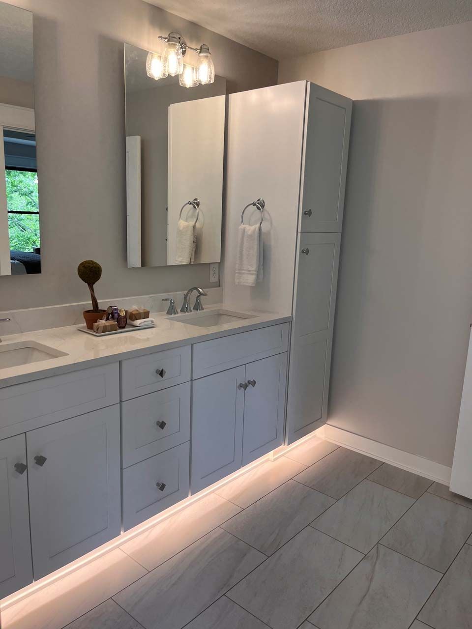 Bathroom with white cabinets, light gray walls, and under-cabinet lighting.
