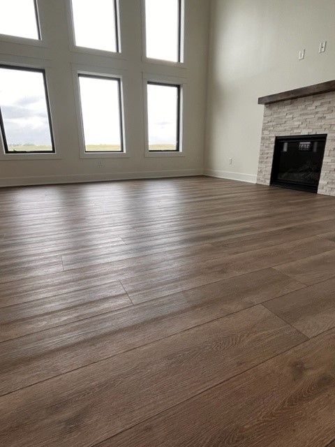 An empty living room with hardwood floors and a fireplace.
