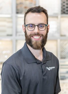 A man with a beard and glasses is wearing a black polo shirt.