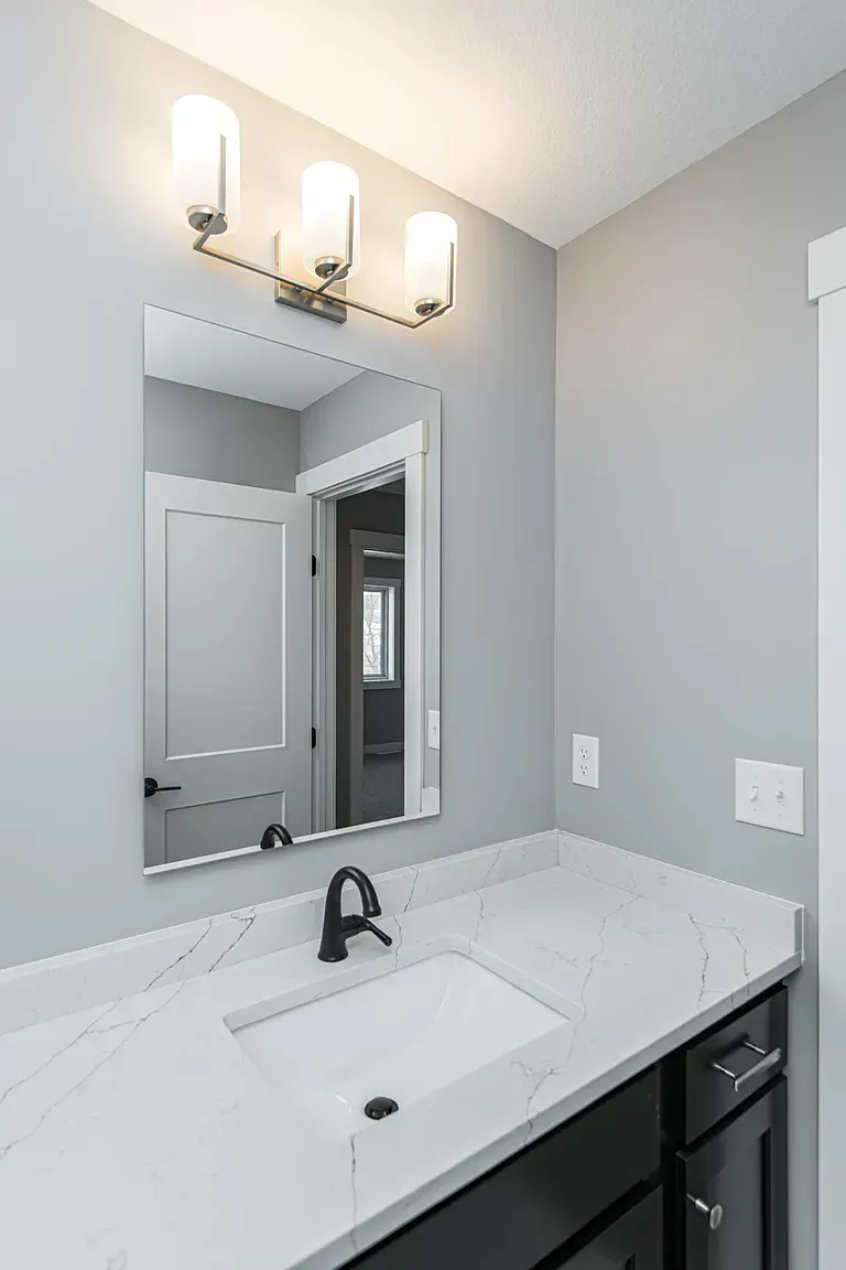 A bathroom with a sink , mirror and light fixtures.