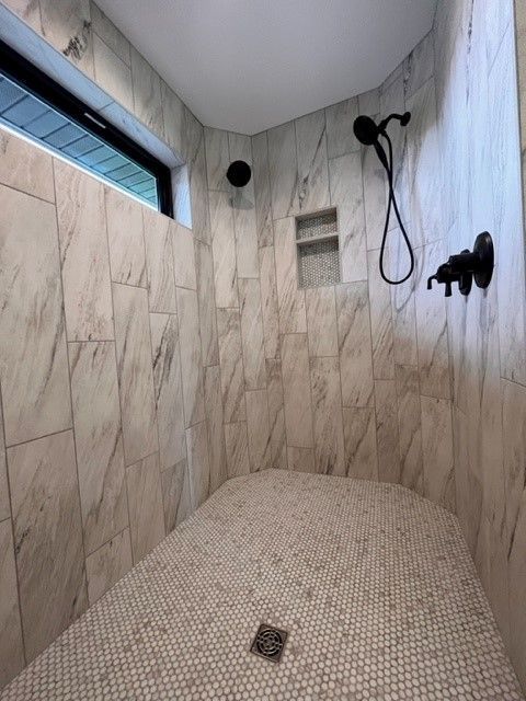 A walk in shower with marble tiles and a window