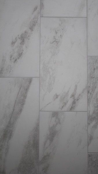 A close up of a white tile floor with a marble texture.