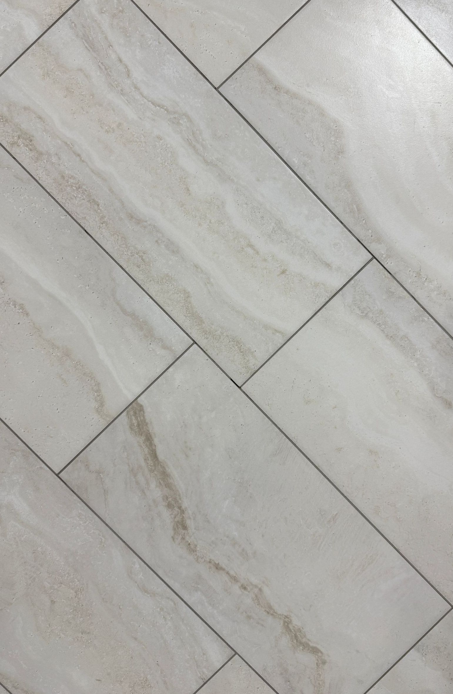 A close up of a white tile floor with a diagonal pattern.