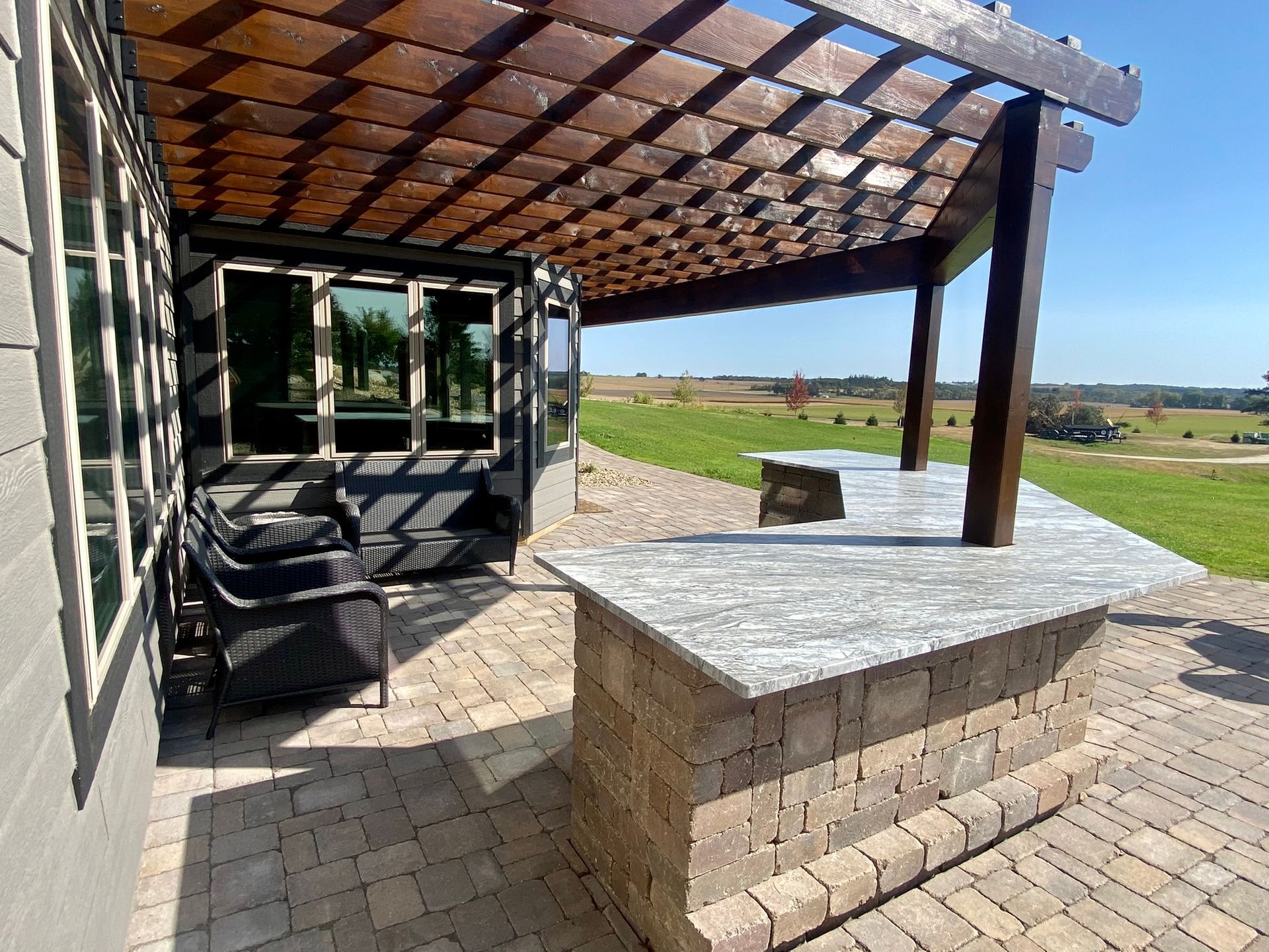 A patio with a pergola and a table with a view of a field.