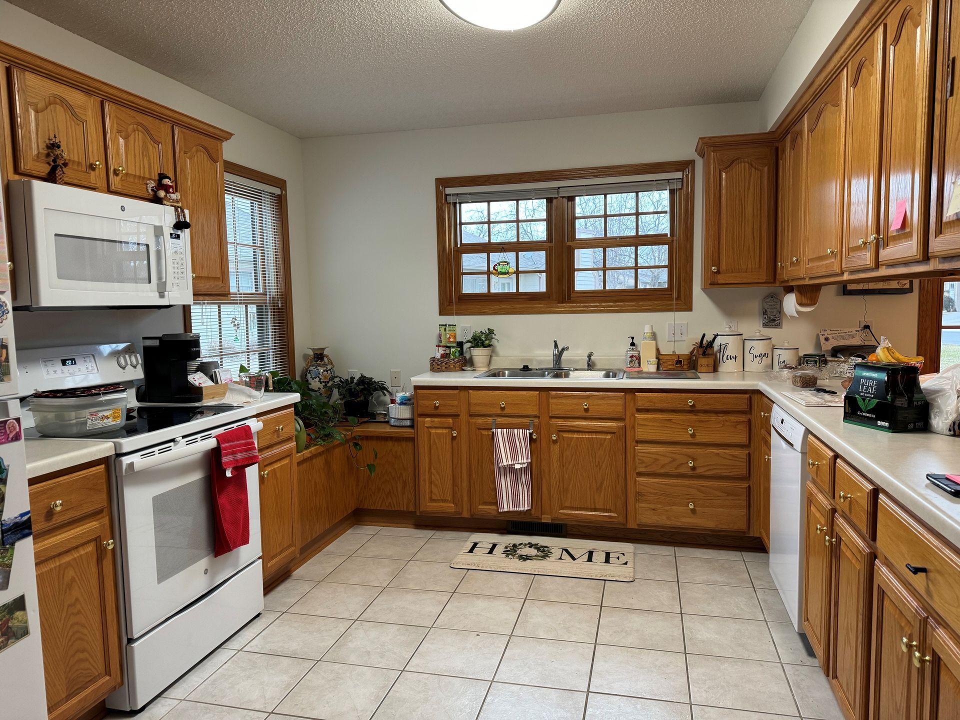 Kitchen with light-colored cabinets, white appliances, and a window above the sink.