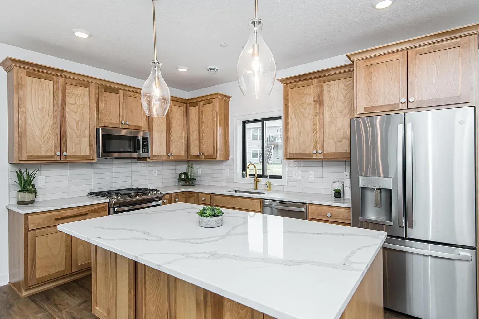 A kitchen with wooden cabinets , stainless steel appliances , and a large island.