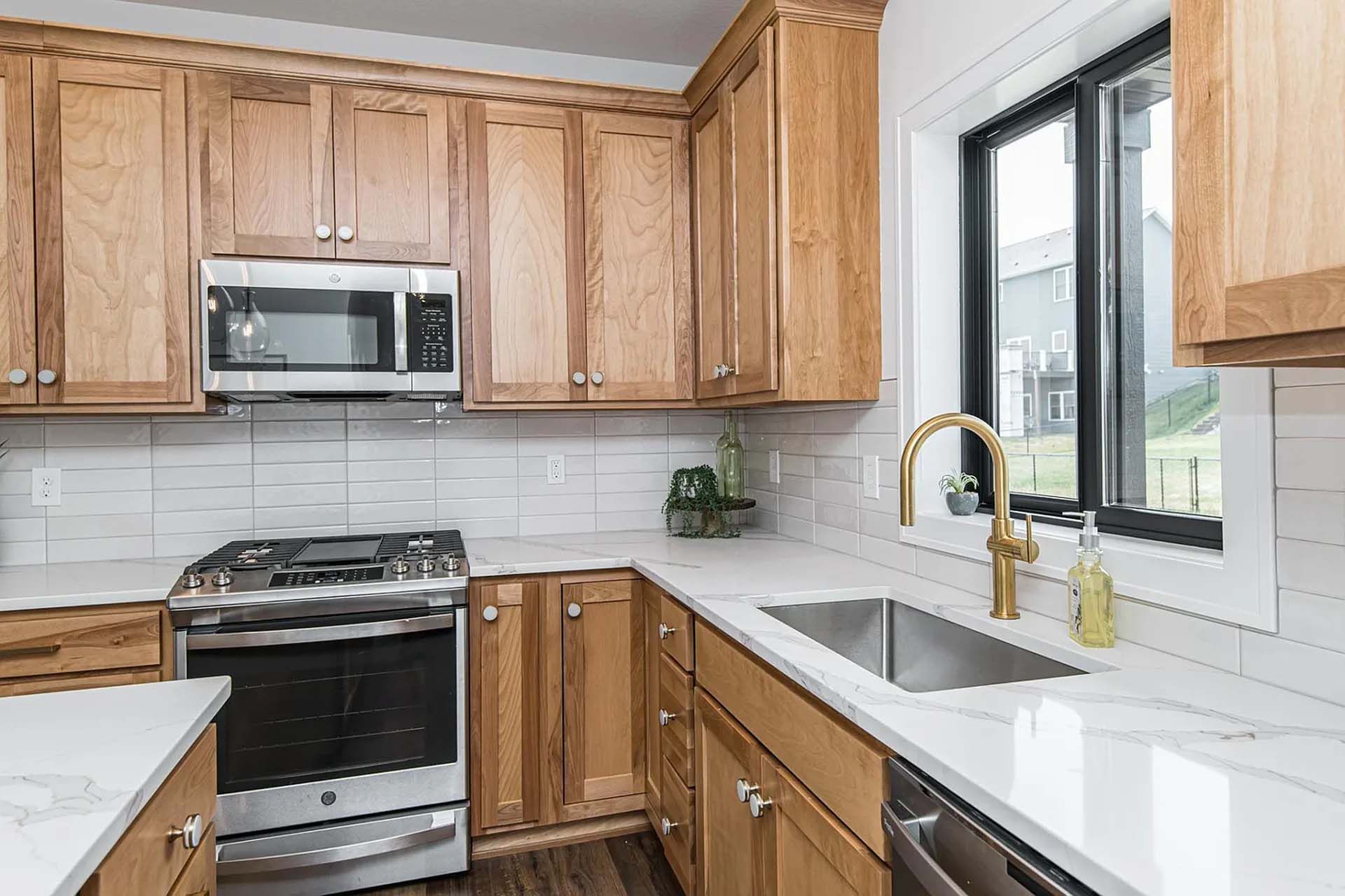 A kitchen with wooden cabinets , stainless steel appliances , a sink , and a window.