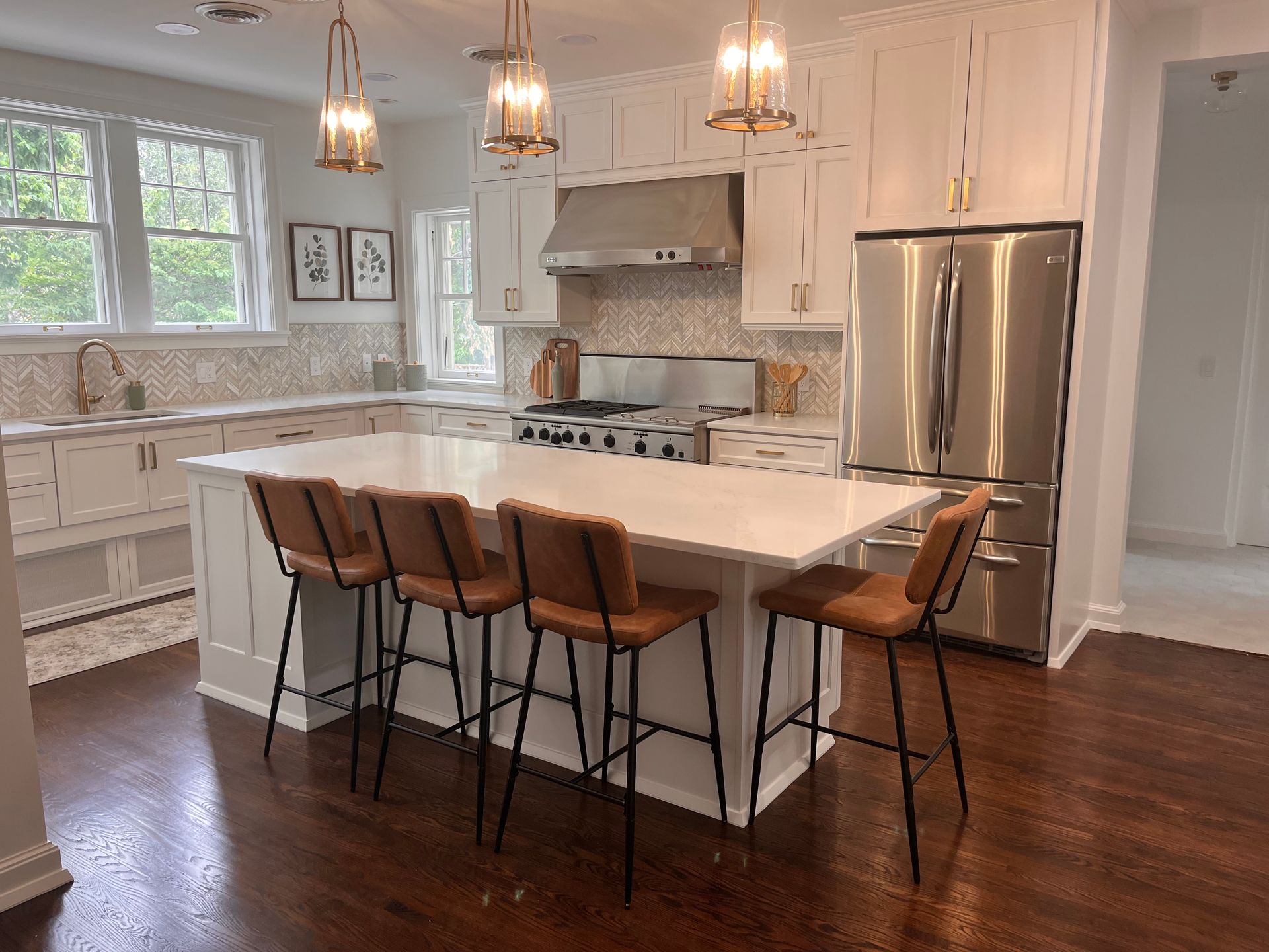 Modern kitchen with white cabinets, island with brown bar stools, and stainless steel appliances.